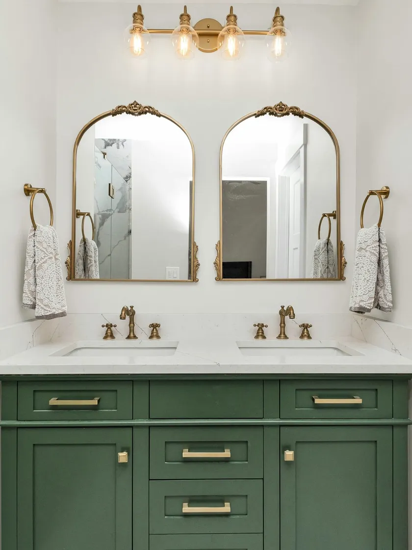 White marble double vanity top on an emerald green cabinet with brass fixtures in Alpharetta, GA